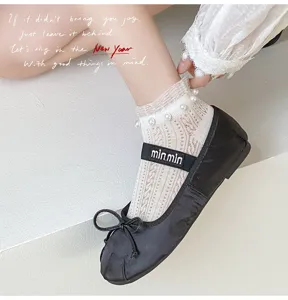 Close-up of delicate white lace mesh ankle socks with pearl decor paired with black shoes.