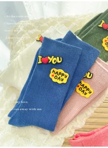 Close-up detail of trendy colorful ribbed mid-calf socks featuring cute silicone letter patches.