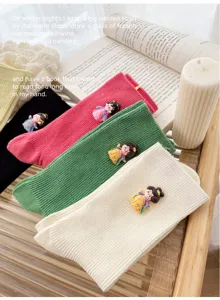 Detail shot of cute ribbed slouch socks with traditional doll decoration, soft knit casual style.