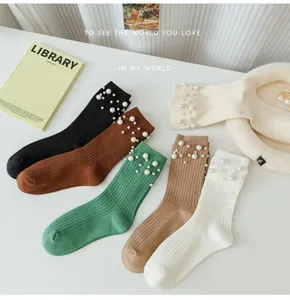 Gros plan de chaussettes élégantes pour femmes avec des perles délicates sur les poignets.