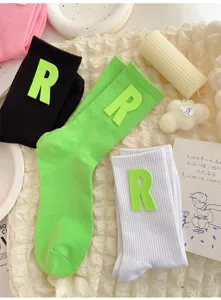 Detail shot of cute mid-calf socks featuring a large 3D letter R patch and soft ribbed knit.