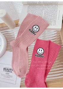 Pink ribbed mid-tube socks featuring a cute smiley face and happy letter patch design.