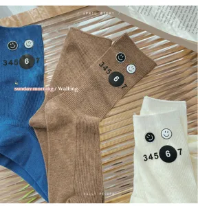 Detail view of cute college style casual mid-tube stacked socks with smiley face and numbers.