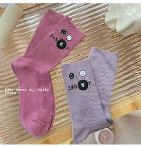 Close-up detail of cute ribbed mid-tube slouch socks with smiley face and number prints.