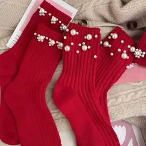 Red knit socks for women, trendy winter mid-tube hosiery with elegant pearl cuff decor.