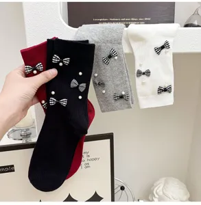 Detail shot of sweet bow and pearl decorated mid-calf socks, stylish and cute daily wear.