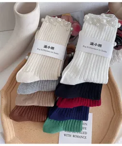 Close-up of stylish women mid-tube socks featuring delicate pearls and rhinestones on cuffs.