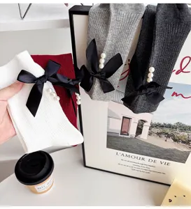 Detail view of knitted socks featuring elegant black bow and pearl decoration close up