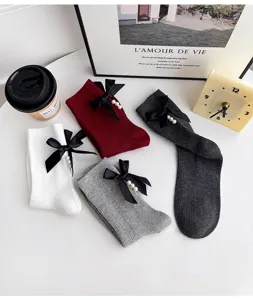Detailed view of cute knit mid-calf socks featuring elegant black bow and pearl decor.