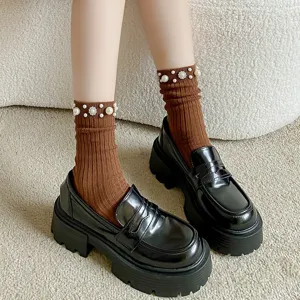 Stylish women brown ribbed mid tube socks with pearl beads paired with black platform loafers.