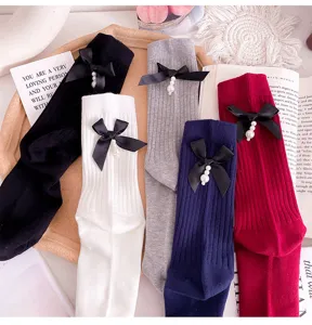 Knit mid-calf socks featuring black bow and pearl pendant details, perfect for cute styling.