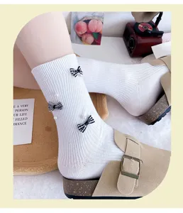 Detailed view of white mid-calf socks featuring cute plaid bows and elegant pearl decorations.