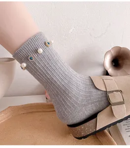 Detail shot of grey ribbed mid-calf socks decorated with pearls and blue crystal rhinestones.