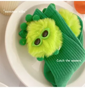 Cute green socks detail featuring fluffy plush monster doll and funny glasses design.