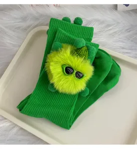 Cute green mid-tube socks with furry monster doll and pom-pom decor for women stylish wear.