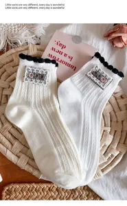 Close-up of Japanese cute white socks featuring black ruffle cuffs and chic button lace patch.