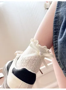 Detail shot of women sweet lace mesh short socks with white ribbon cross bow and heart pearl.