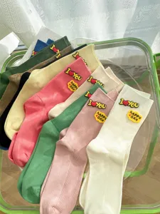 Trendy women's mid-tube socks featuring cute silicone letter patches and colorful striped design.