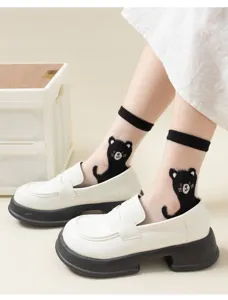 Close-up detail of sheer black cat crystal silk socks worn with stylish white loafers.
