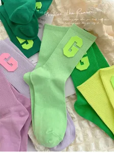 Detail view of trendy college style women socks featuring bold letter G patch and high elastic cuff.