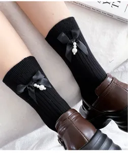 Detailed view of women's black mid-calf socks featuring elegant ribbon bows and faux pearl pendants.