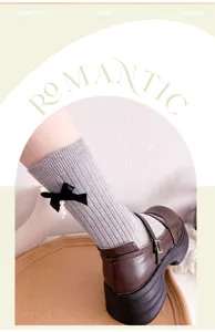 Grey ribbed socks with black bow and pearl pendant detail, paired with stylish brown shoes.