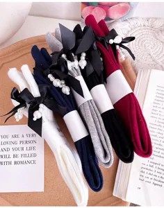 Detail of cotton mid-calf socks featuring elegant black ribbon bows and pearl pendants.