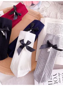 Women ribbed mid-calf socks featuring black bow and pearl pendant, chic autumn winter knit hosiery.