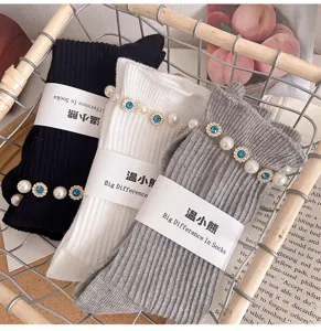 Detailed view of stylish knit mid-calf socks decorated with pearls and blue rhinestones.
