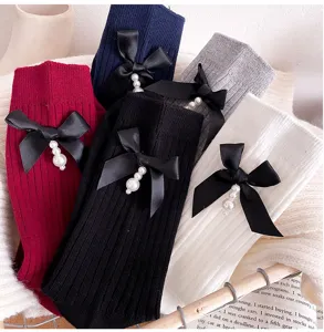 Detail view of cotton mid-calf socks with black ribbon and pearl pendants, stylish footwear.