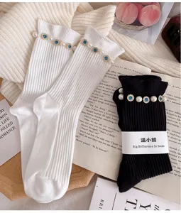 Close-up detail of stylish women mid-tube socks with elegant pearl and rhinestone trim design.
