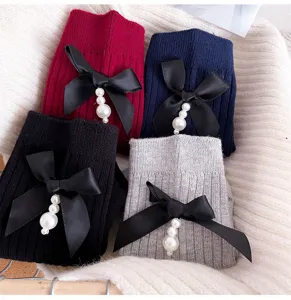 Close-up detail of women ribbed mid socks with black bow and pearl pendant design for winter.