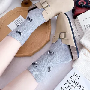 Women grey ribbed mid-tube socks with cute bow and pearl charms paired with beige clogs.