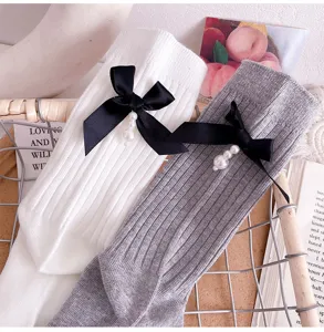 Detailed shot of women knit mid-tube socks featuring elegant black bows and pearl pendants.