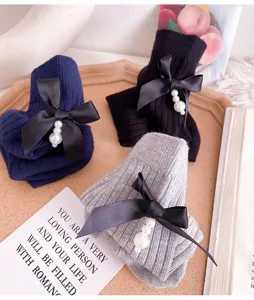 Detailed view of women's knit mid-tube socks featuring elegant black ribbon and pearl pendants.