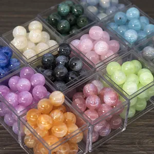 Close-up detail of colorful glitter resin round beads in clear boxes for DIY jewelry making.