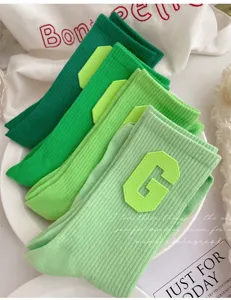 Close-up of vibrant green ribbed crew socks featuring a stylish collegiate letter patch detail.