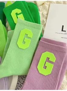 Trendy college style green and purple mid-calf socks for women with letter G patch.