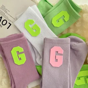 Ribbed cotton knit crew socks featuring bold letter G patches, colorful versatile design.