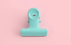 Detalle de pinza metálica verde menta para papel, clip colorido para papelería y uso diario.