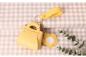 Detailed close-up of mini PU leather handbag keychain with cute flower mirror charm.