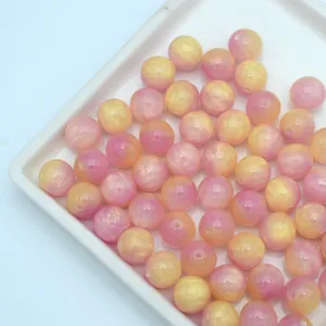Close-up detail of pink and yellow swirled resin round beads for DIY handmade jewelry accessories.