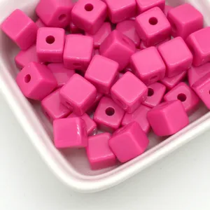 Gedetailleerde close-up van glanzende roze acryl vierkante kralen voor DIY sieraden maken.