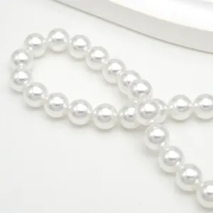 Détail en gros plan de perles de verre nacrées blanches, idéales pour la création de bijoux DIY.