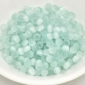 Close-up view of 4mm light green cat eye glass spacer beads for DIY craft jewelry making.