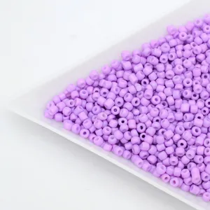 Close up of purple seed barrel beads in a white sorting tray for DIY handmade jewelry making.
