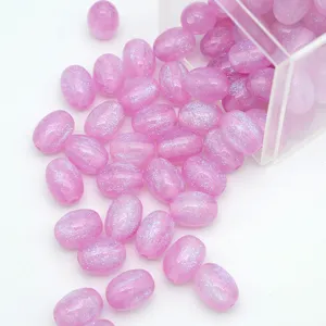 Vue détaillée de perles ovales en résine violette pailletée sortant d'une boîte, pour bijoux DIY.