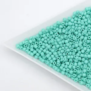 Close-up detail view of cyan glass seed beads neatly arranged in a white sorting tray.