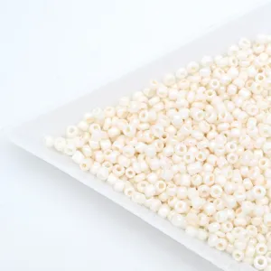 Close-up of milky white glass seed beads in a white tray, perfect for DIY jewelry making.