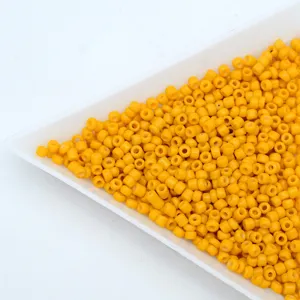 Close-up detail of yellow glass seed beads, solid barrel beads for DIY handmade jewelry bracelets.